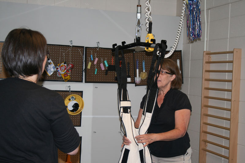 Demonstration of a special harness for a disabled child to stand in.